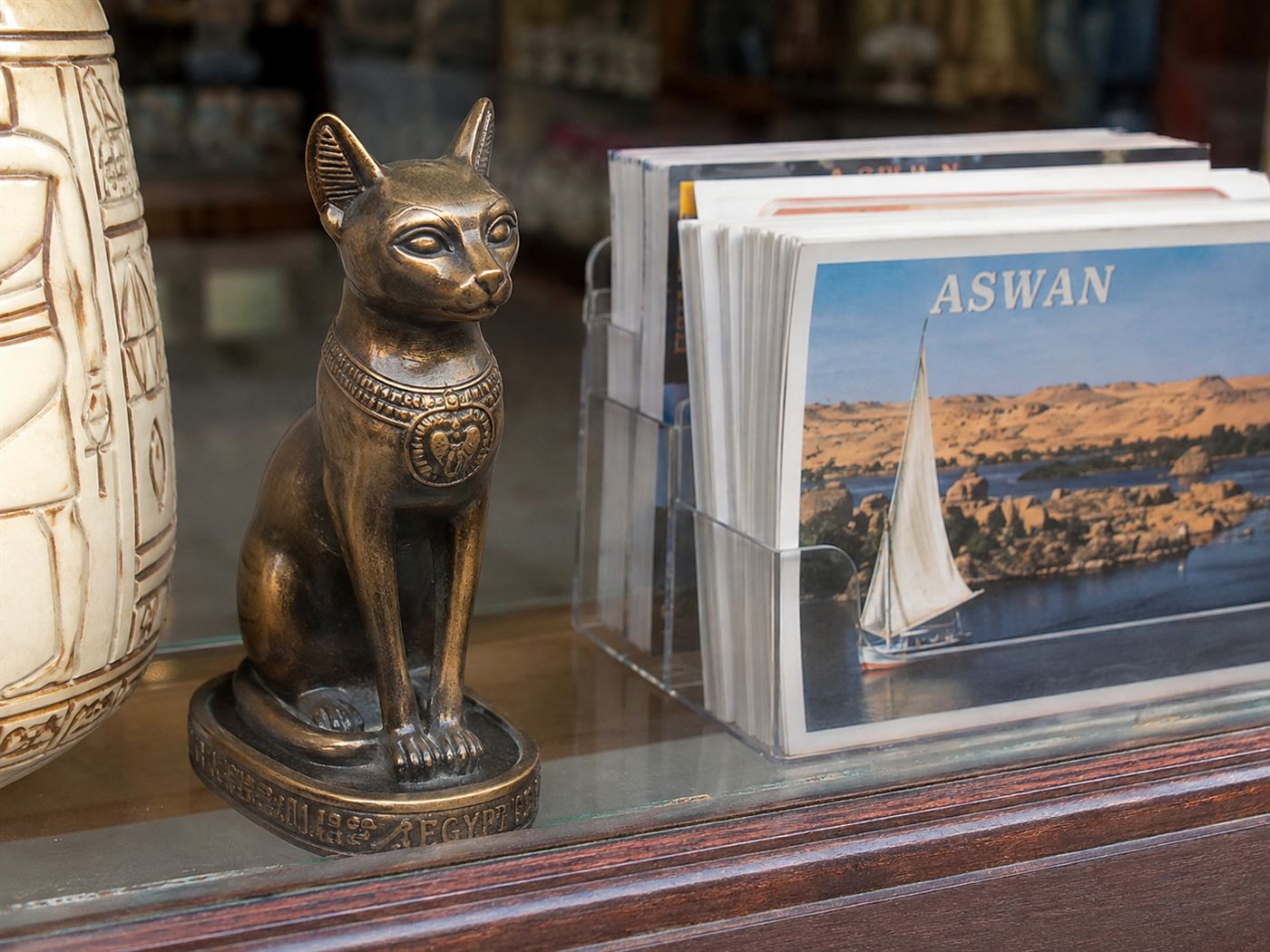 A bronze Egyptian cat statue beside ancient stone temple ruins